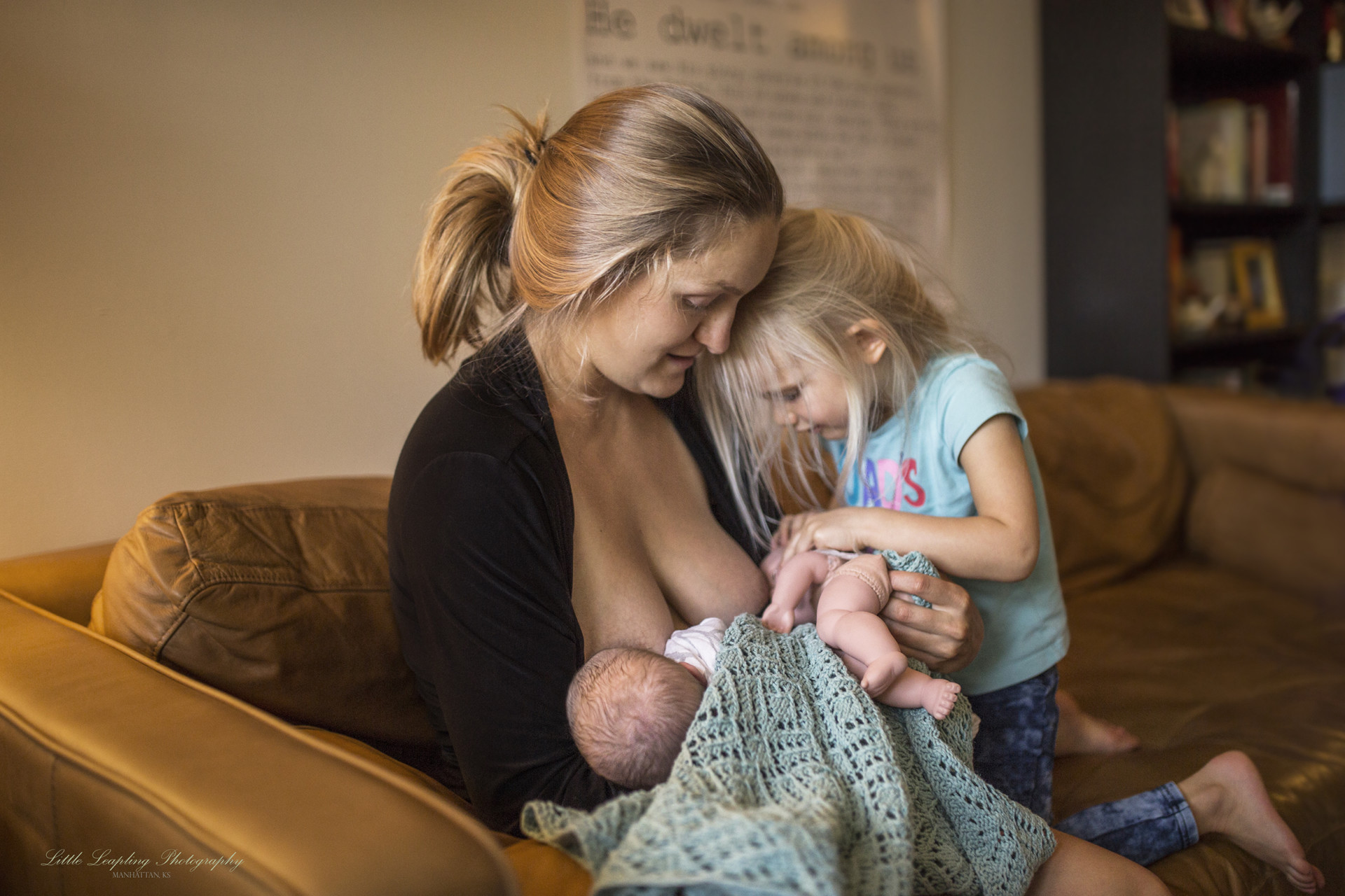 une mère allaite son nouveau-né, son autre fille joue à faire téter sa poupée à l'autre sein