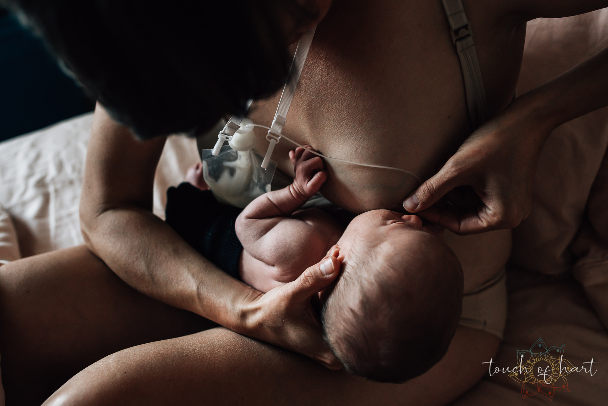 Une mère allaite son nourrisson avec un dispositif d'aide à la lactation